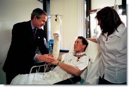 President George W. Bush shakes hands with Army SFC Thomas Douglas of Fayetteville, N.C., after presenting him with the Purple Heart at Walter Reed Army Medical Center in Washington, D.C., Friday, April 11, 2003. Also pictured is Mr. Douglas' wife, Donna Douglas. White House photo by Eric Draper.